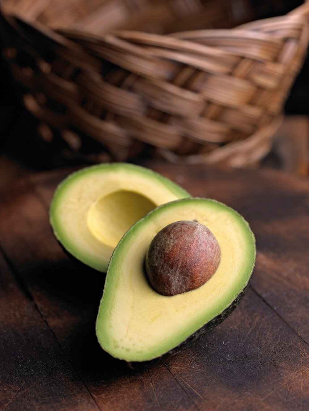 A halved avocado on a dark wooden board
